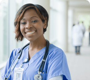 healthcare worker in light blue scrubs smiling in hospital